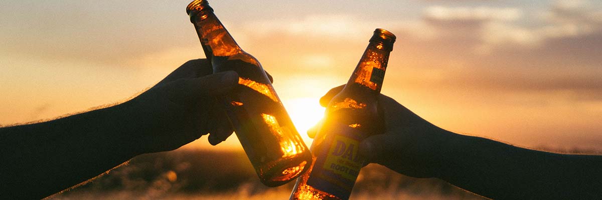 2 people sharing glass bottle root beers at sunset