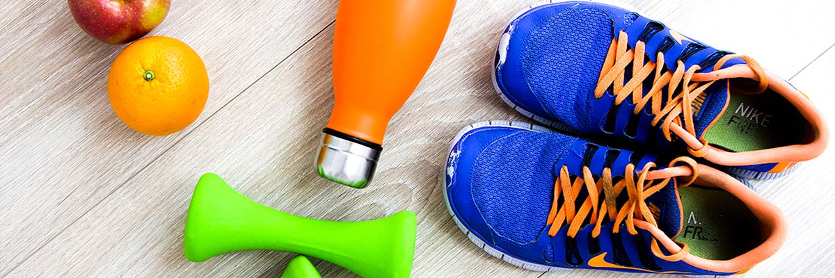 colorful blue tennis shoes with orange laces, green hand weights, orange water bottle, and an orange and an apple