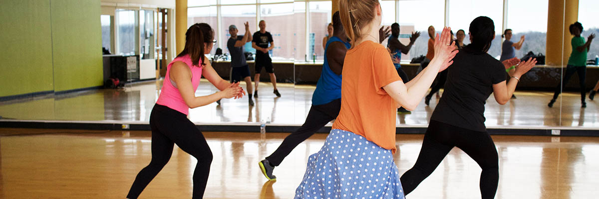 4 people stepping to the right and clapping in a group fitness class