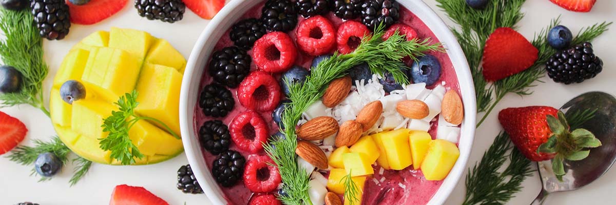 bowl full of fruit and nuts surrounded by more fruit and nuts on a table