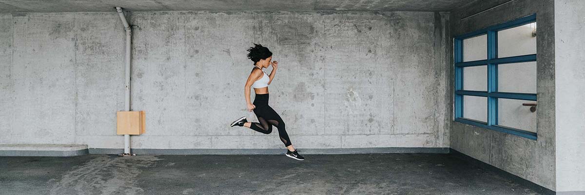 girl in mid air jumping for distance while running