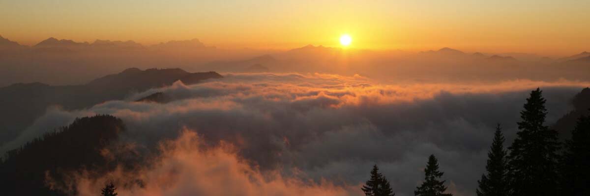 beautiful sunrise over cloud covered mountains below