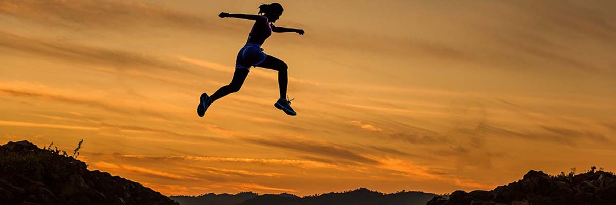 girl outdoor in sunrise leaping across canyon