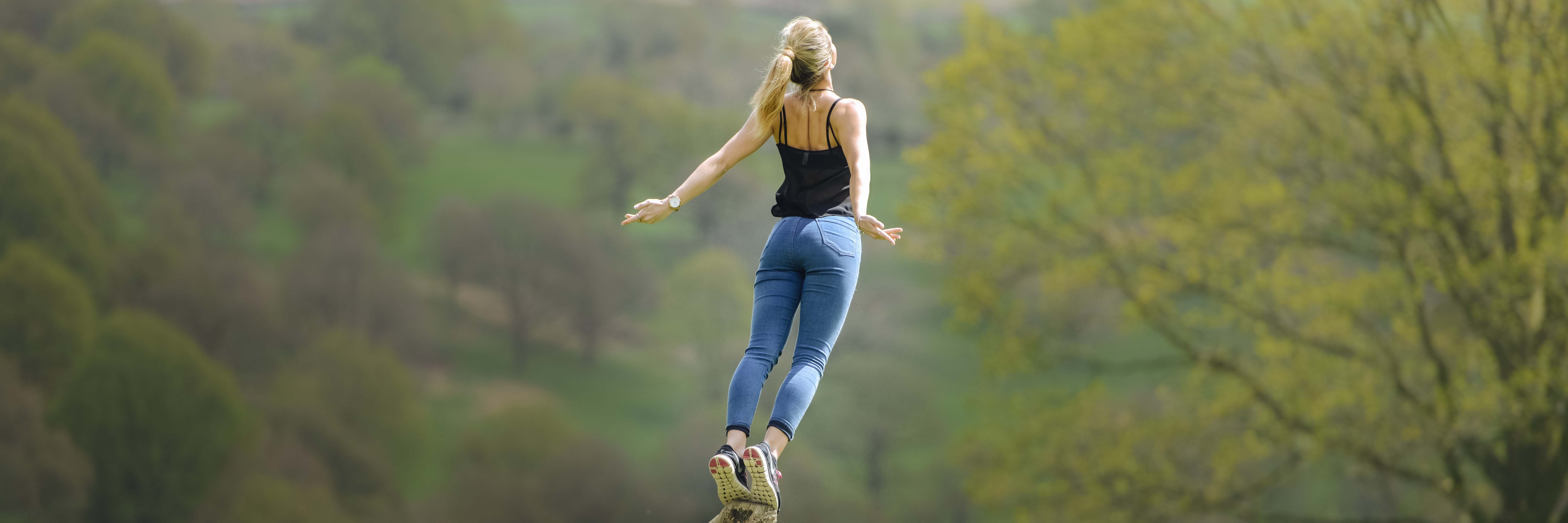 woman balancing on tip of rock