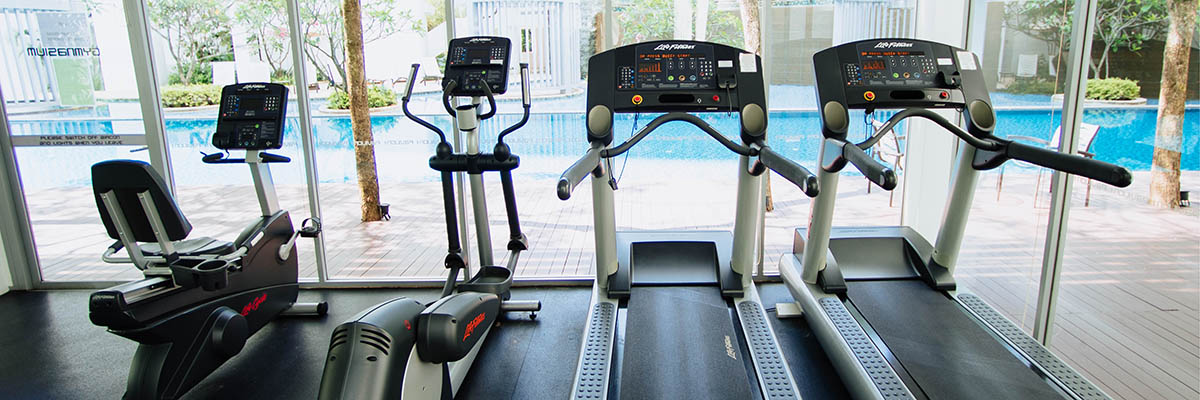 indoor cardio equipment looking out a floor to ceiling winow at an outdoor pool