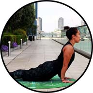 girl doing yoga pose on yoga mat stretching back with palms of hands on floor