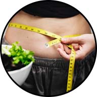 lady measuring herself with a tape measure around the waist while holding a bowl full of salad