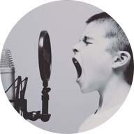 Boy yelling into podcast booth microphone