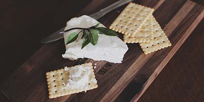 cutting board with 4 crackers and pie sliced shaped wedge of white cheese