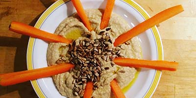 bowl of hummus with 8 carrot slices arranged in perfectly spaced circular pattern
