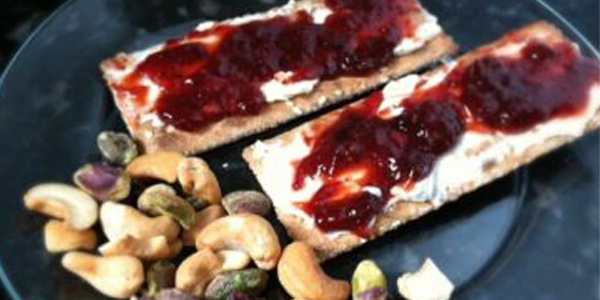 Whole wheat crackers with cream cheese and strawberry preserves with mixed nuts on the side: