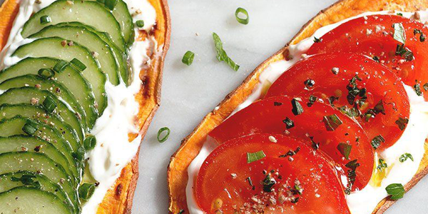 Two slices of oblong toast with cream cheese and one with tomato and one with cucumber