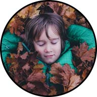 young boy taking a nap in a leaf pile