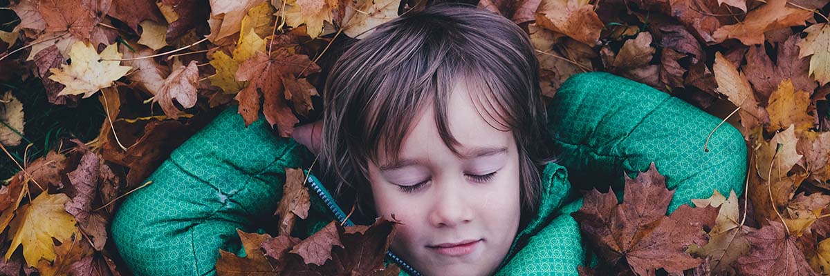 young boy taking a nap in a leaf pile