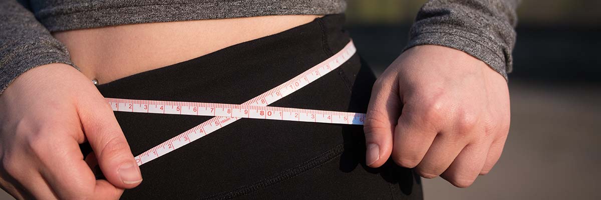 close up of woman with cloth tape measure around her waist